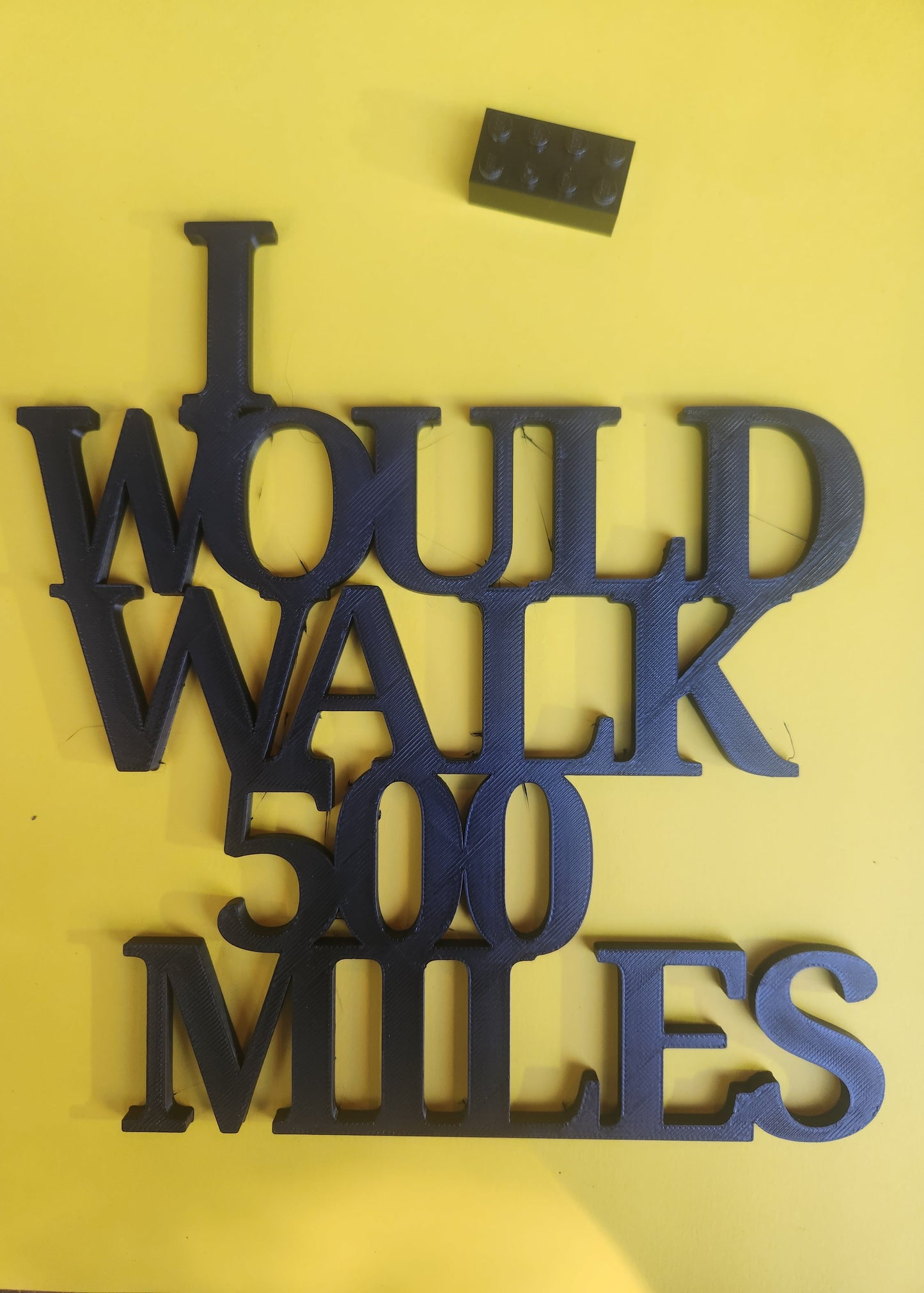 Image 2 (Scale Shot): Yellow background with Lego brick — navy sign displayed with scale reference