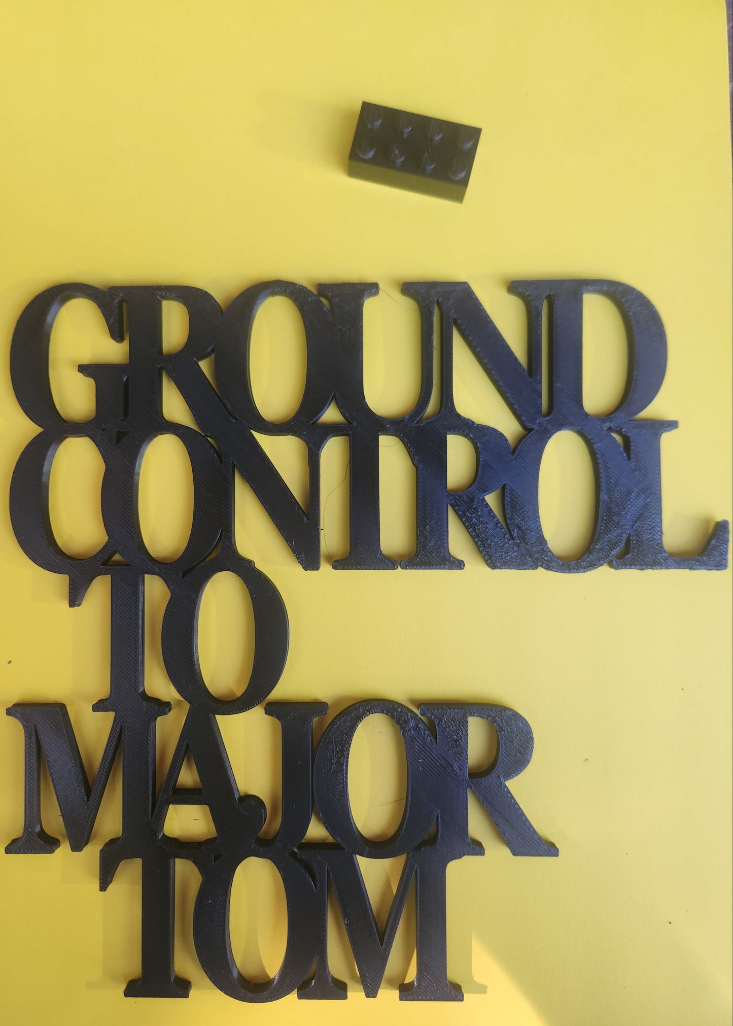 3D printed sign with a standard Lego brick placed beside it for scale reference, demonstrating the compact 19cm size (Lego brick not included with purchase)