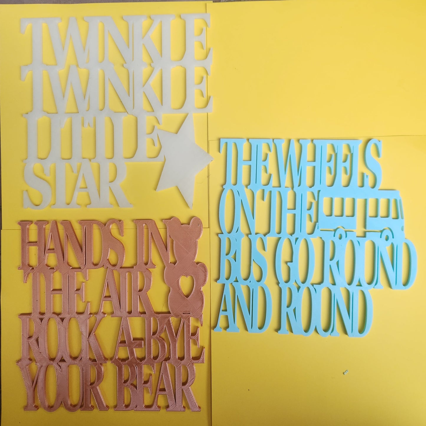  Three 3D printed nursery rhyme wall art signs — Twinkle Twinkle Little Star
     in glow in the dark, Rock-A-Bye Your Bear in rose gold, and Wheels on the Bus
     in sky blue — displayed together, handmade in Upper Hutt New Zealand, 19cm x 19cm each