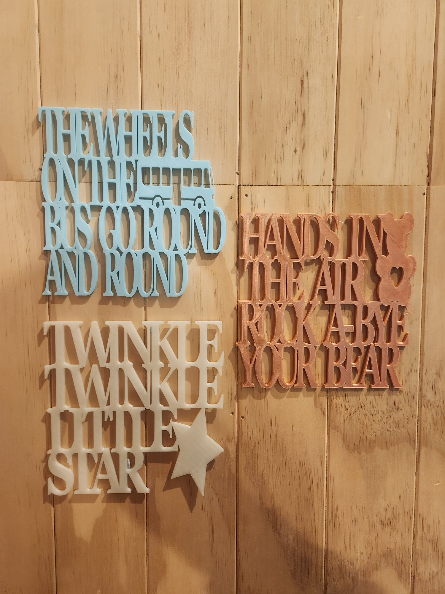  Three 3D printed nursery rhyme wall art signs — Twinkle Twinkle Little Star
     in glow in the dark, Rock-A-Bye Your Bear in rose gold, and Wheels on the Bus
     in sky blue — displayed together, handmade in Upper Hutt New Zealand, 19cm x 19cm each