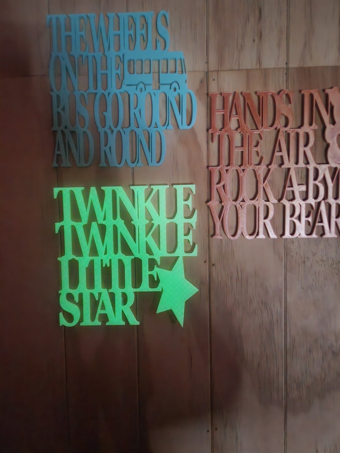  Three 3D printed nursery rhyme wall art signs — Twinkle Twinkle Little Star
     in glow in the dark, Rock-A-Bye Your Bear in rose gold, and Wheels on the Bus
     in sky blue — displayed together, handmade in Upper Hutt New Zealand, 19cm x 19cm each