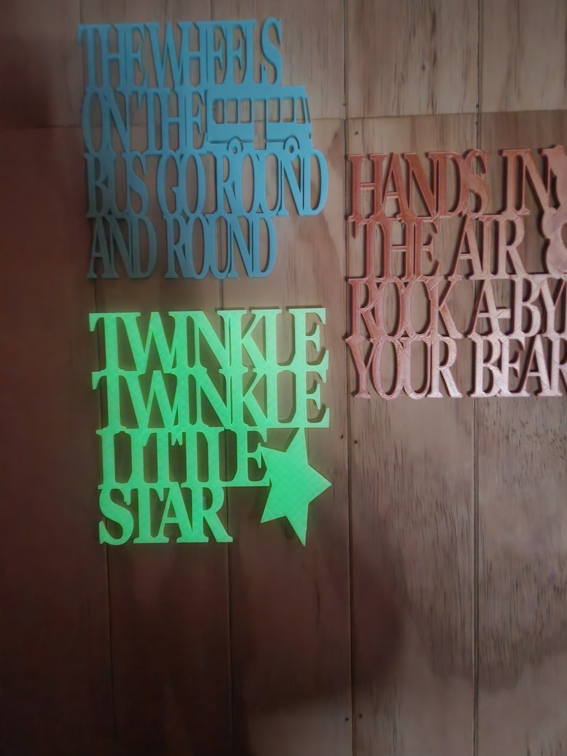  Three 3D printed nursery rhyme wall art signs — Twinkle Twinkle Little Star
     in glow in the dark, Rock-A-Bye Your Bear in rose gold, and Wheels on the Bus
     in sky blue — displayed together, handmade in Upper Hutt New Zealand, 19cm x 19cm each
