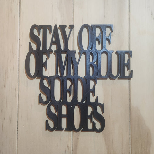 Black PLA 'Stay Off Of My Blue Suede Shoes' 3D printed wall art sign mounted on whitewashed wood wall, chunky serif lettering