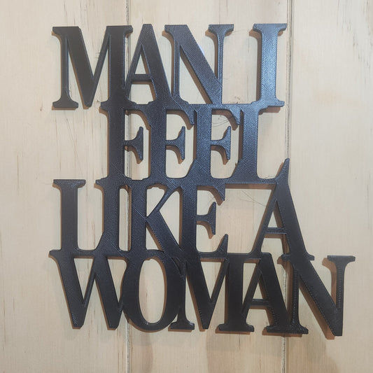 Black 3D printed 'Man I Feel Like a Woman' wall art sign mounted on whitewashed wood wall, 190mm × 190mm