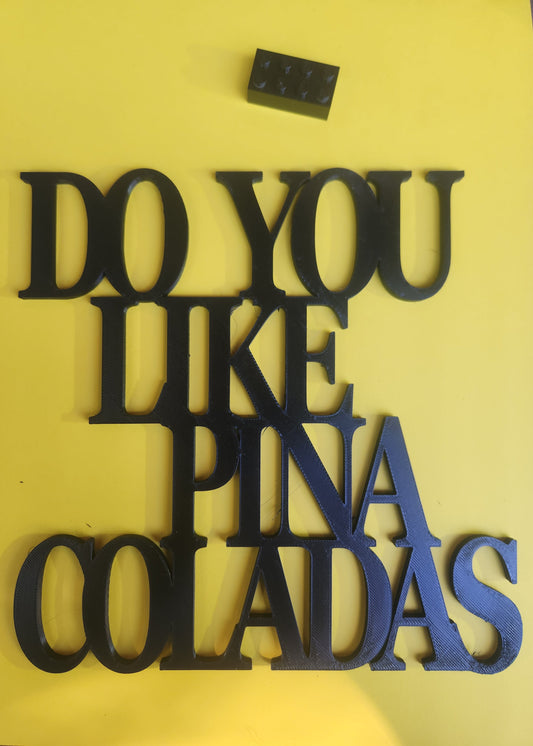 Do You Like Piña Coladas wall art sign in yellow, shown with Lego brick for size reference (190mm × 190mm)