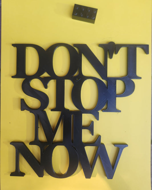 Overhead view of black 'Don't Stop Me Now' 3D printed sign with Lego brick for size reference