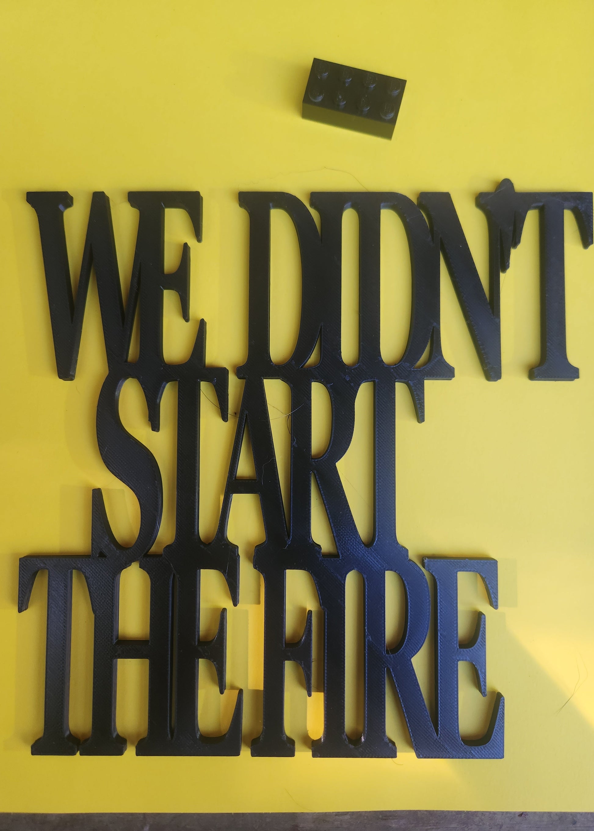 We Didn't Start the Fire 3D printed wall art sign in black PLA with a Lego brick for scale (approximately 19cm × 19cm)