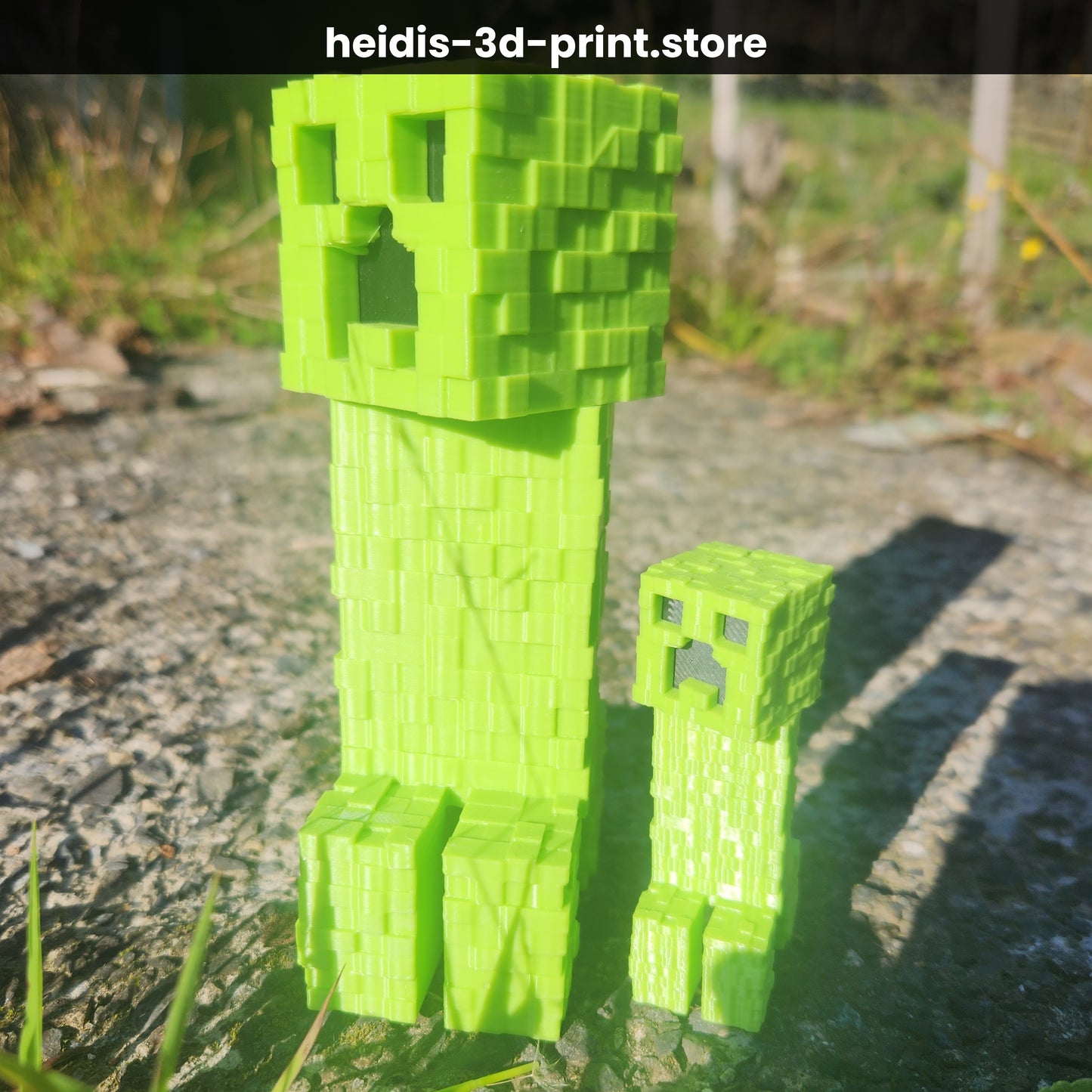 Close-up of two 3D printed Minecraft Creeper figures in green, showing the iconic blocky pixel face texture, Upper Hutt NZ