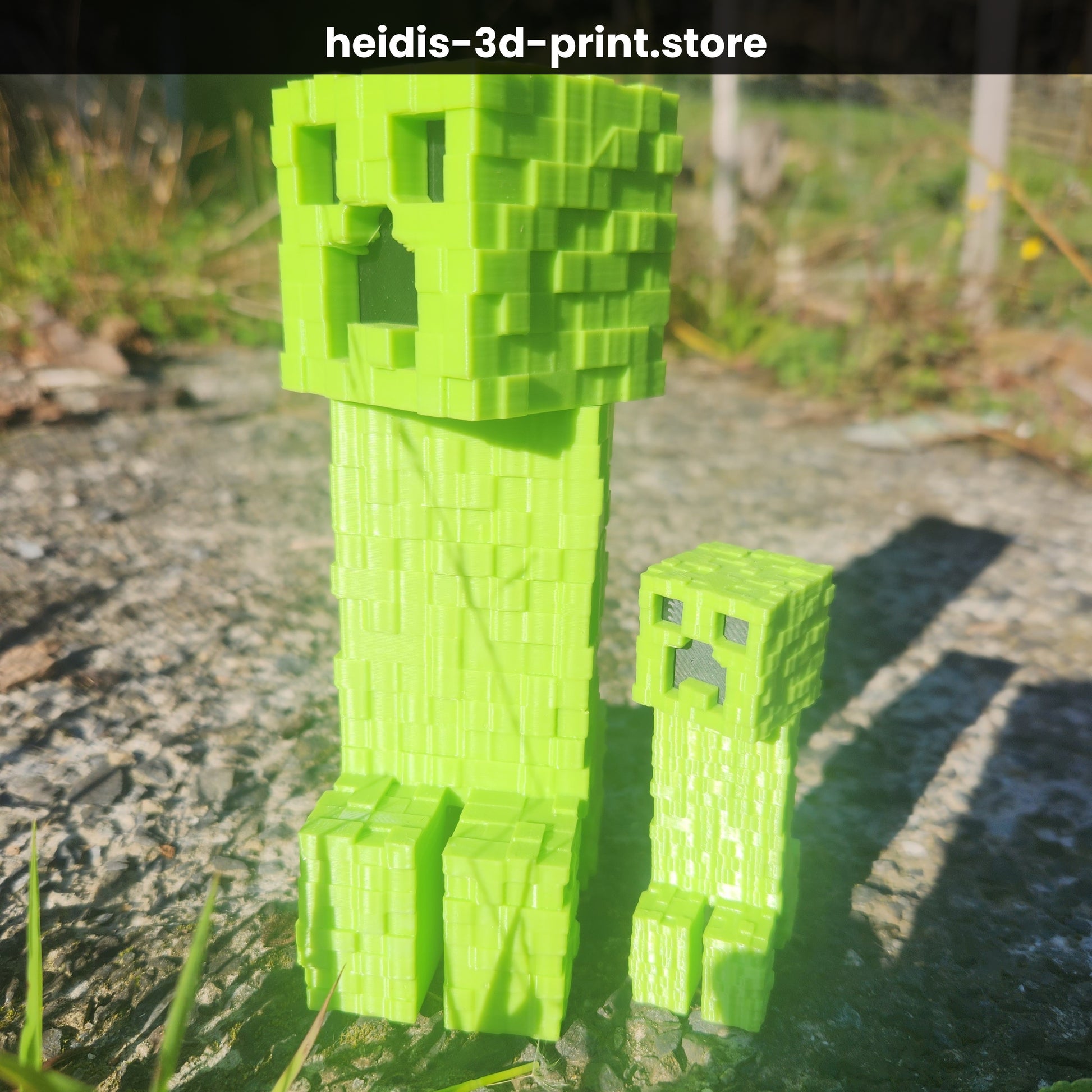 Close-up of two 3D printed Minecraft Creeper figures in green, showing the iconic blocky pixel face texture, Upper Hutt NZ
