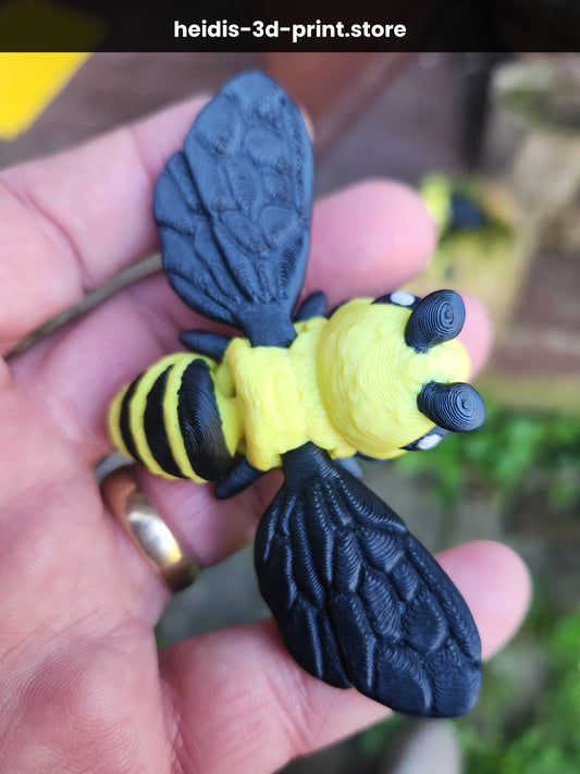 Hand holding a medium 3D printed articulated bee figure in yellow and black, showing detailed veined wings and moveable body joints, made in Upper Hutt NZ by Heidi's 3D Prints