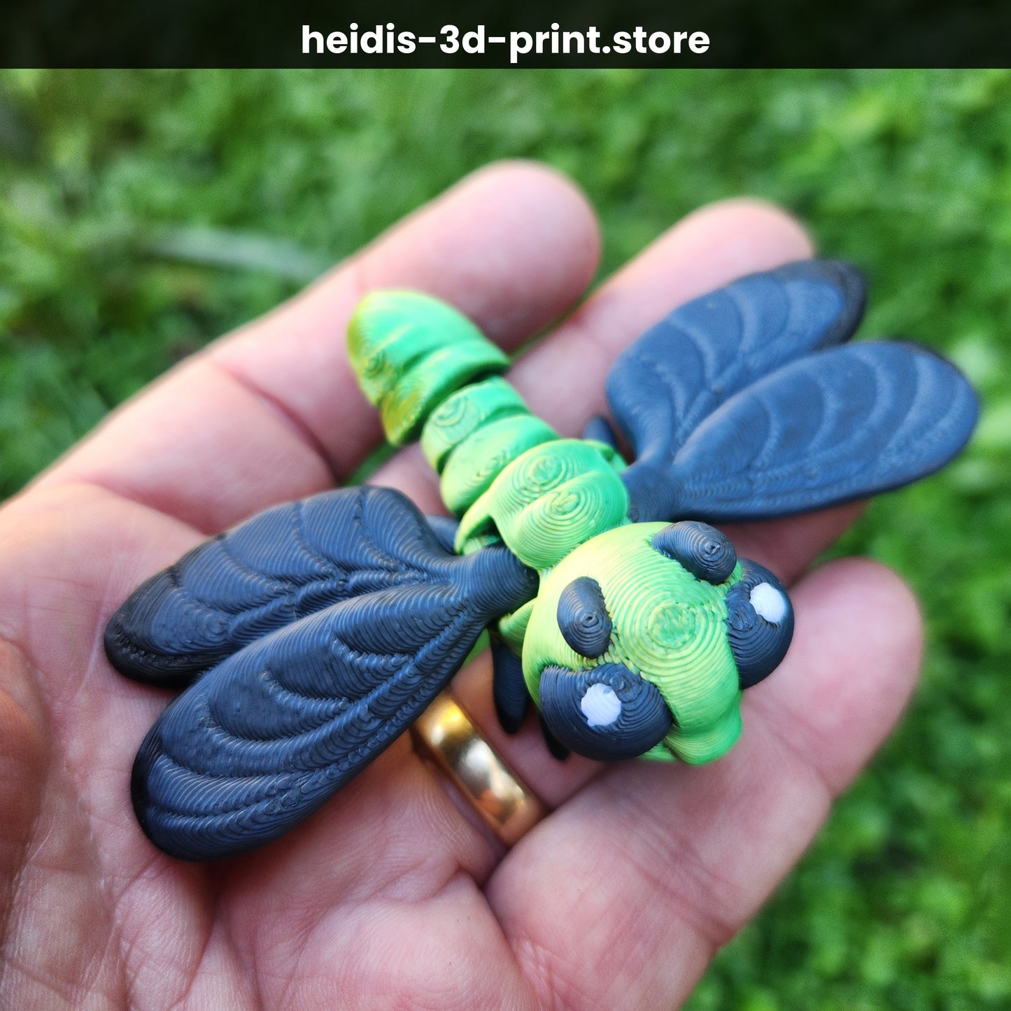 Hand holding a medium 3D printed articulated dragonfly figure in green and dark navy, showing detailed veined wings and moveable body joints, made in Upper Hutt NZ by Heidi's 3D Prints