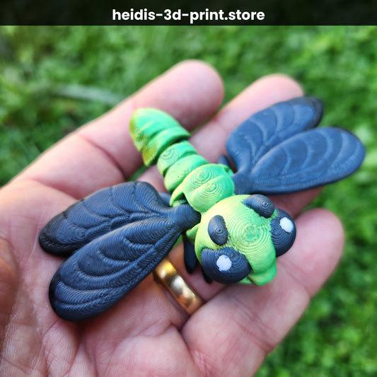 Hand holding a medium 3D printed articulated dragonfly figure in green and dark navy, showing detailed veined wings and moveable body joints, made in Upper Hutt NZ by Heidi's 3D Prints