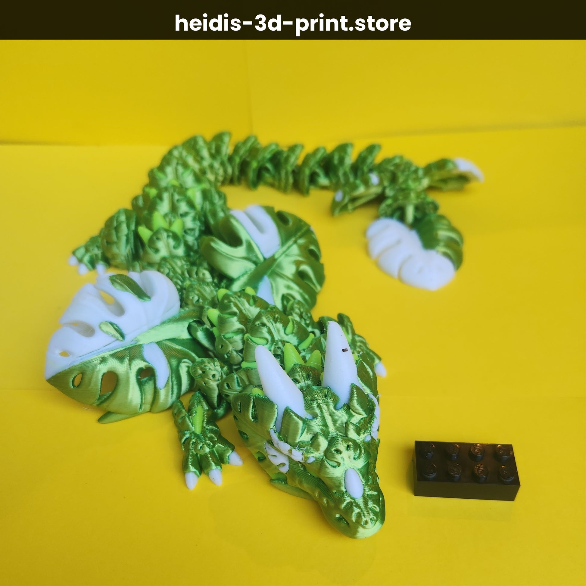 Angled view of 3D printed Monstera Leaf Dragon on yellow background showing head detail, white claws and horns, and full 47cm articulated body, Heidi's 3D Prints Upper Hutt NZ